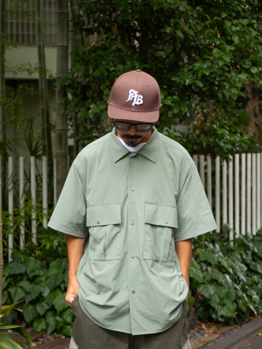 グリーン系のシャツ/ブラウス、グリーン系のカーゴパンツ、ブラウン系のキャップを着用したメンズの夏コーディネートの2枚目の写真