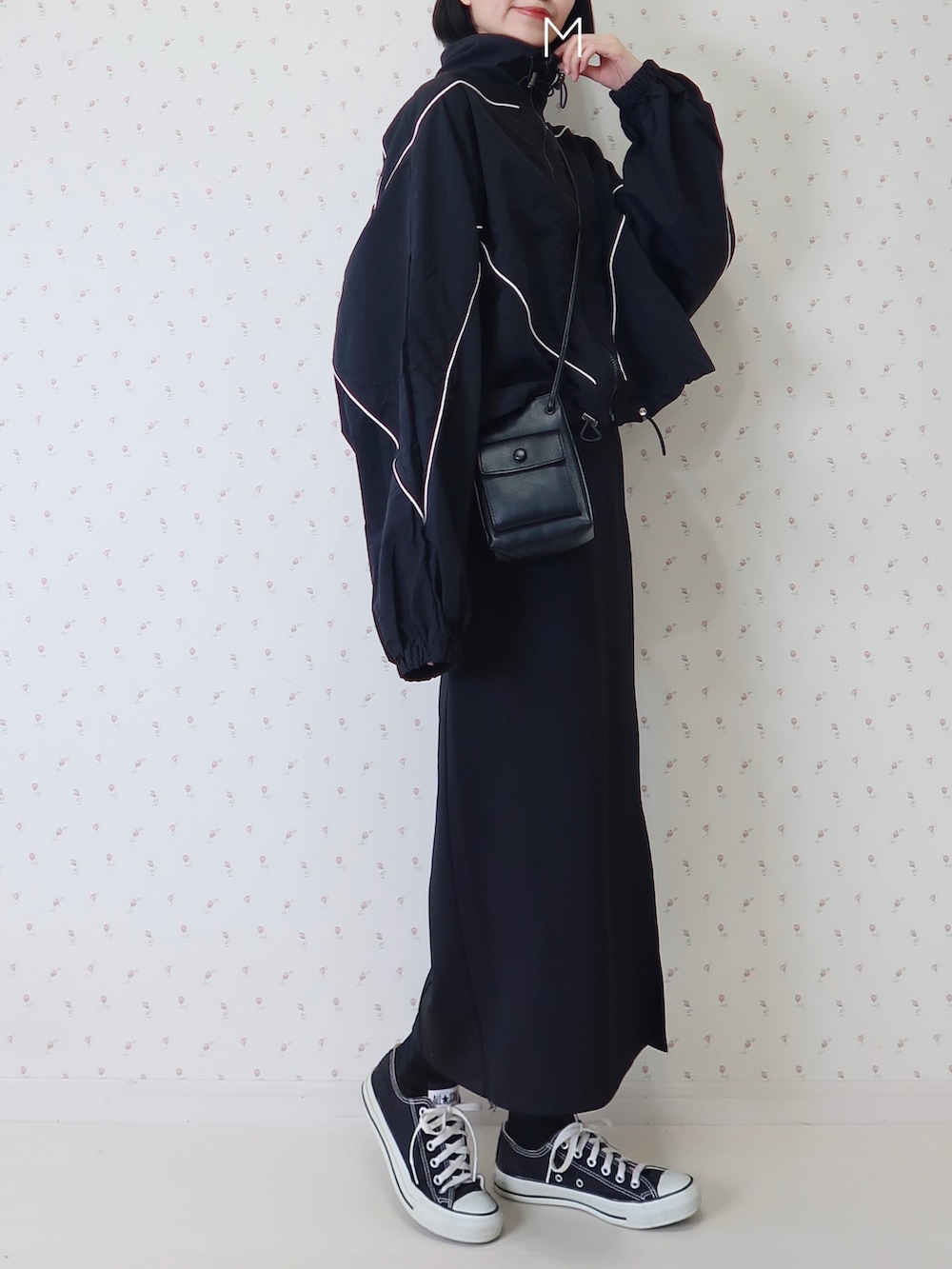 ブラック系のナイロンジャケット、ブラック系のスカート、ブラック系のショルダーバッグを着用したレディースの春コーディネートの2枚目の写真