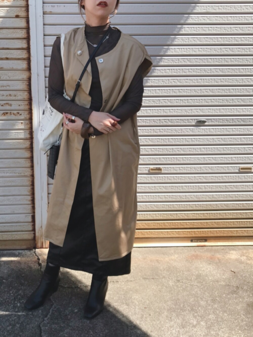 ブラウン系のTシャツ/カットソー、ベージュ系のその他アウター、ブラック系のスカートを着用したレディースの秋コーディネートの2枚目の写真