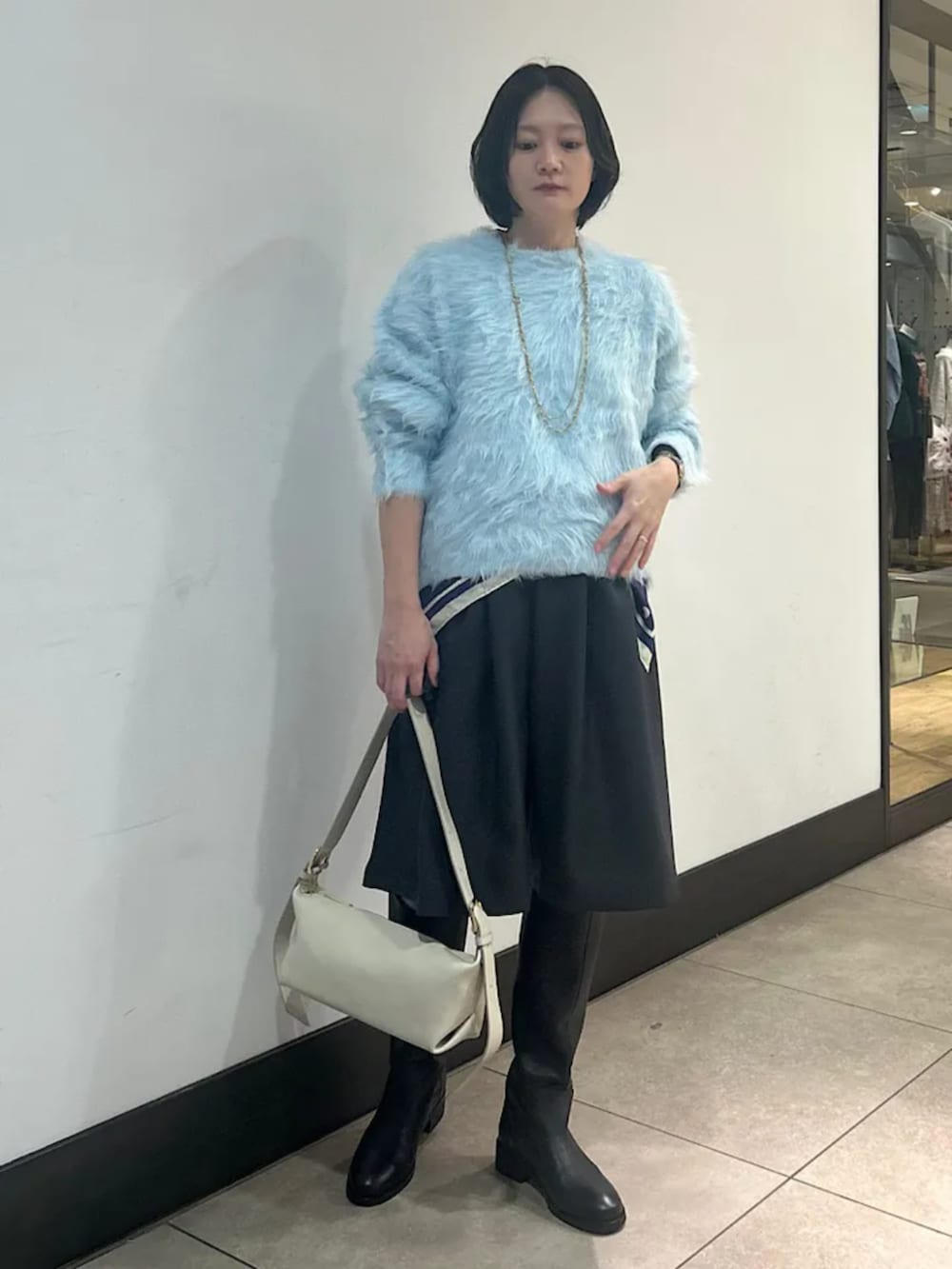 ブルー系のニット/セーター、グレー系のその他パンツ、ブラック系のブーツを着用したレディースの冬コーディネートの2枚目の写真