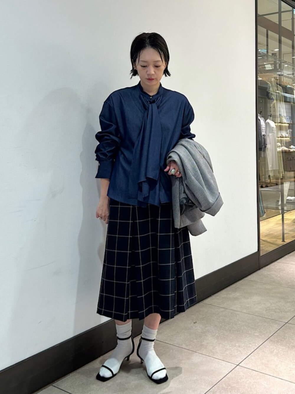 グレー系のテーラードジャケット、ブルー系のシャツ/ブラウス、ブルー系のスカートを着用したレディースの秋コーディネートの2枚目の写真