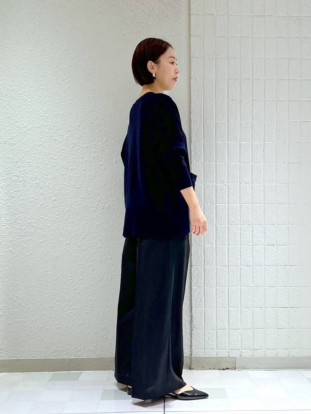 ブラック系のスラックス、ブラック系のパンプス、ブルー系のカーディガン/ボレロを着用したレディースの冬コーディネートの4枚目の写真