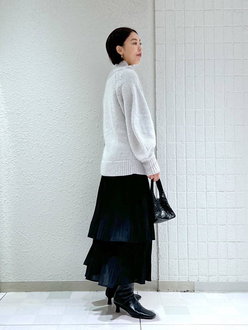 ブラック系のスカート、ブラック系のショルダーバッグ、ブラック系のブーツを着用したレディースの冬コーディネートの2枚目の写真