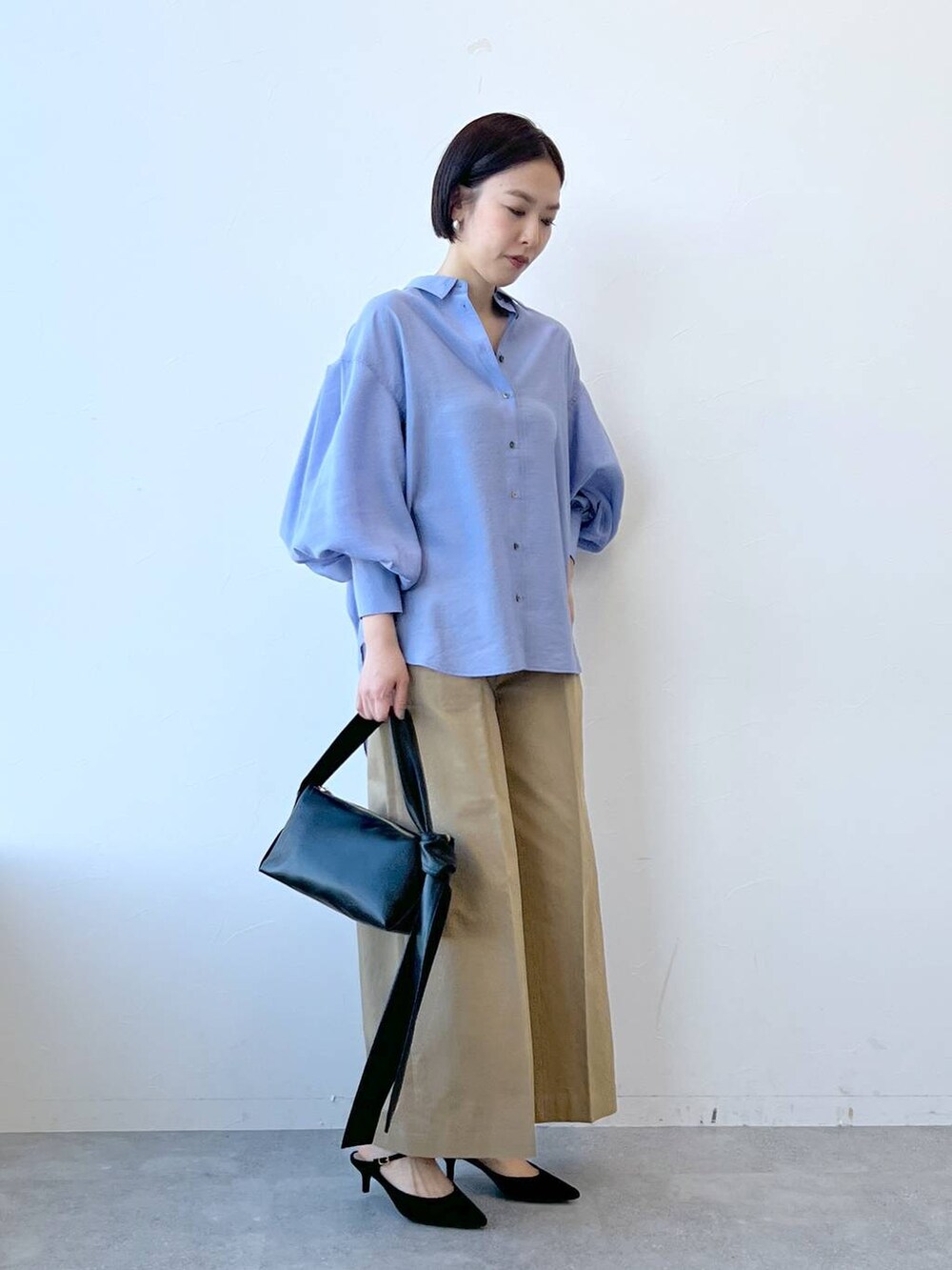 ブラック系のショルダーバッグ、ブラック系のサンダル、ブラウン系のチノパンツを着用したレディースの春コーディネートの3枚目の写真