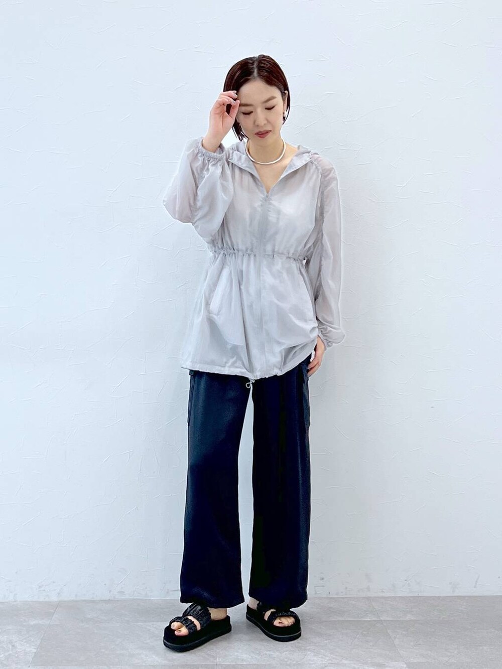 ブラック系のサンダル、グレー系のブルゾン、ブルー系のカーゴパンツを着用したレディースの春コーディネートの2枚目の写真