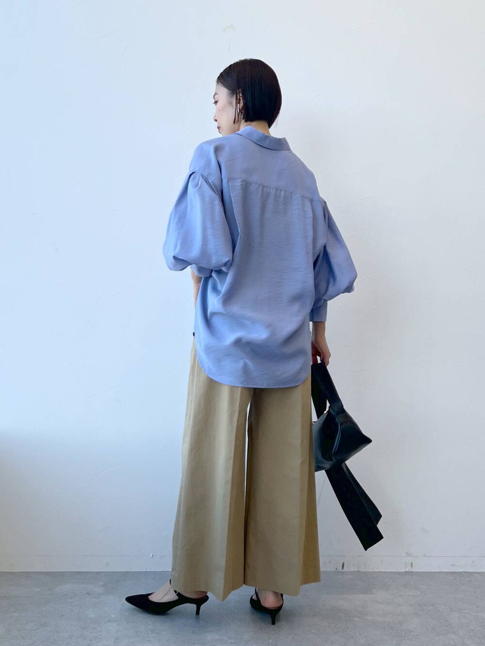 ブラック系のショルダーバッグ、ブラック系のサンダル、ブラウン系のチノパンツを着用したレディースの春コーディネートの2枚目の写真