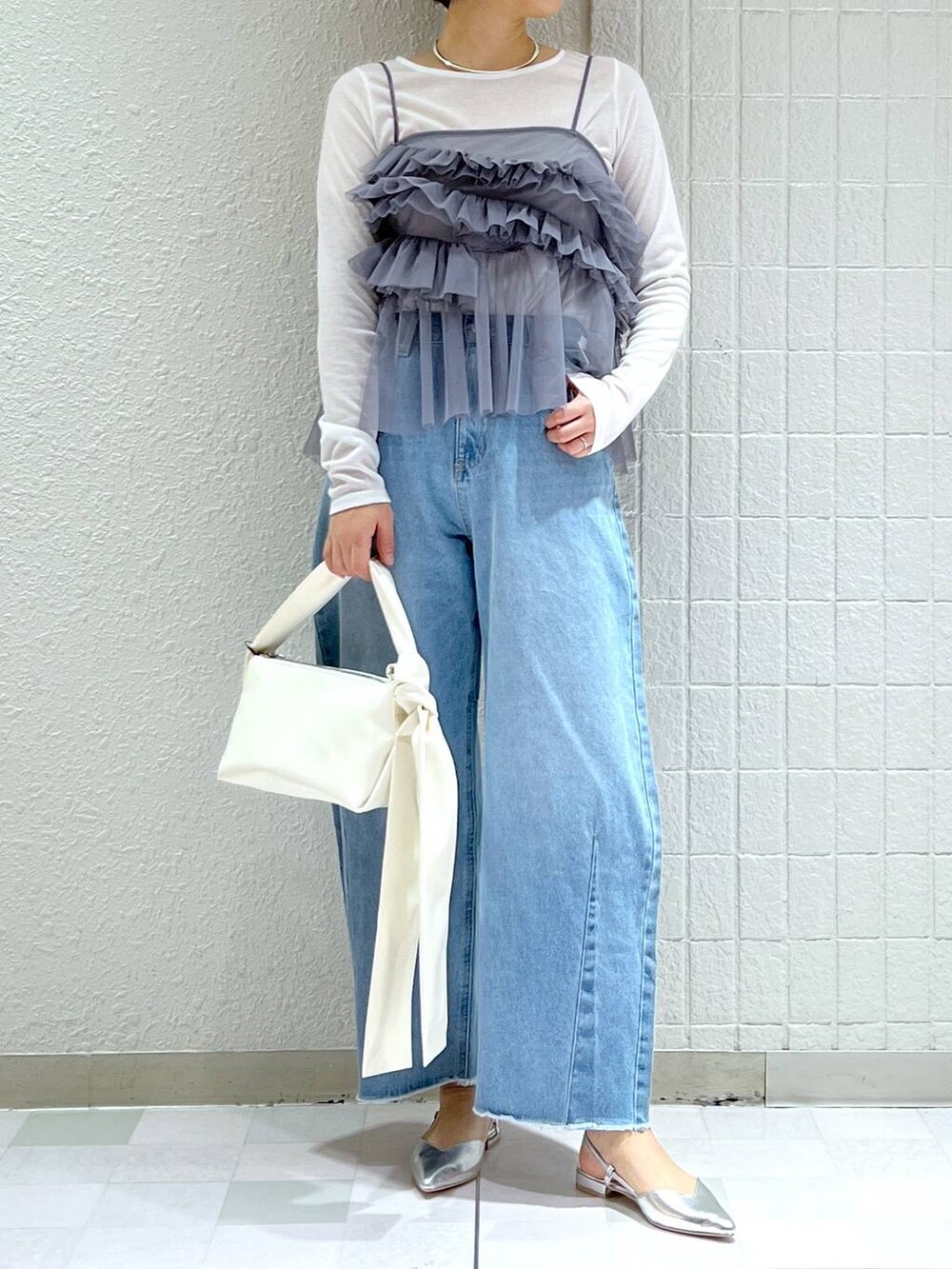 ホワイト系のショルダーバッグ、ブルー系のデニムパンツ、シルバー系のパンプスを着用したレディースの春コーディネートの3枚目の写真