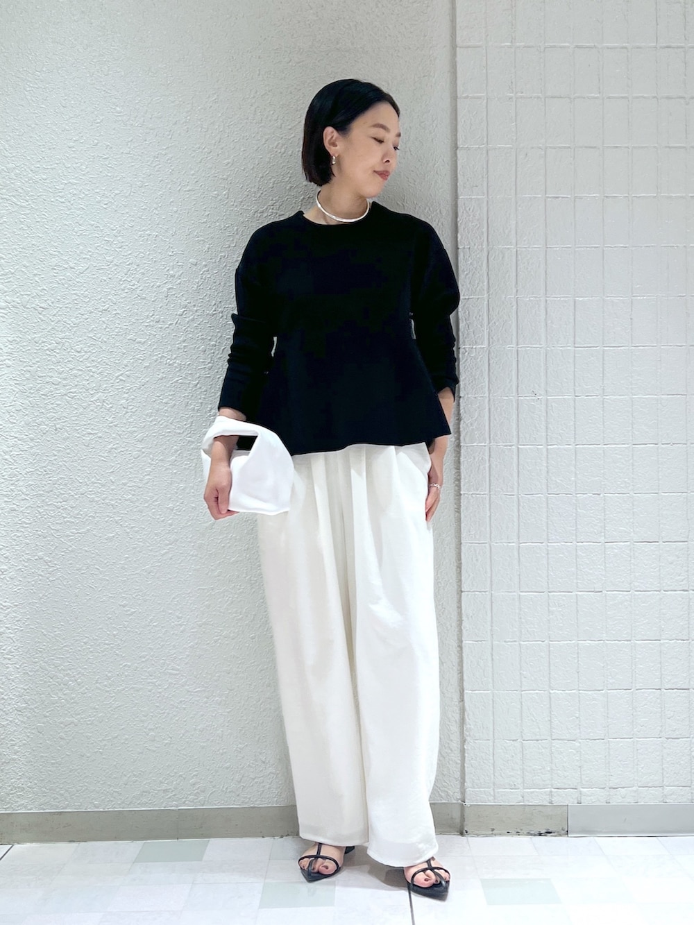 ホワイト系のその他パンツ、ホワイト系のハンドバッグ、ブラック系のニット/セーターを着用したレディースの秋コーディネートの2枚目の写真