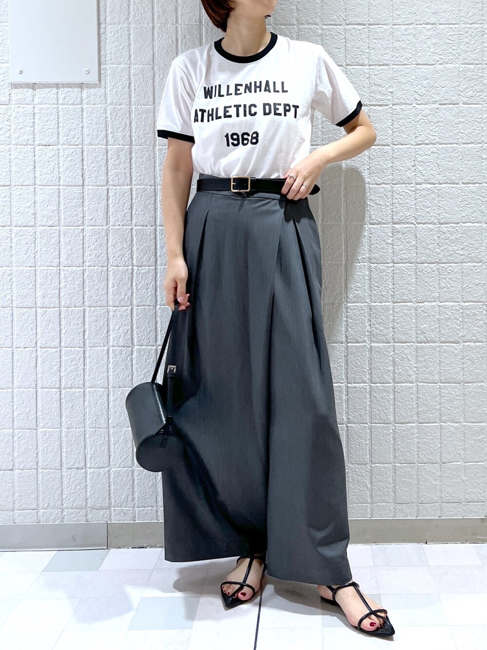 ホワイト系のTシャツ/カットソー、グレー系のスラックス、ブラック系のサンダルを着用したレディースの夏コーディネートの2枚目の写真