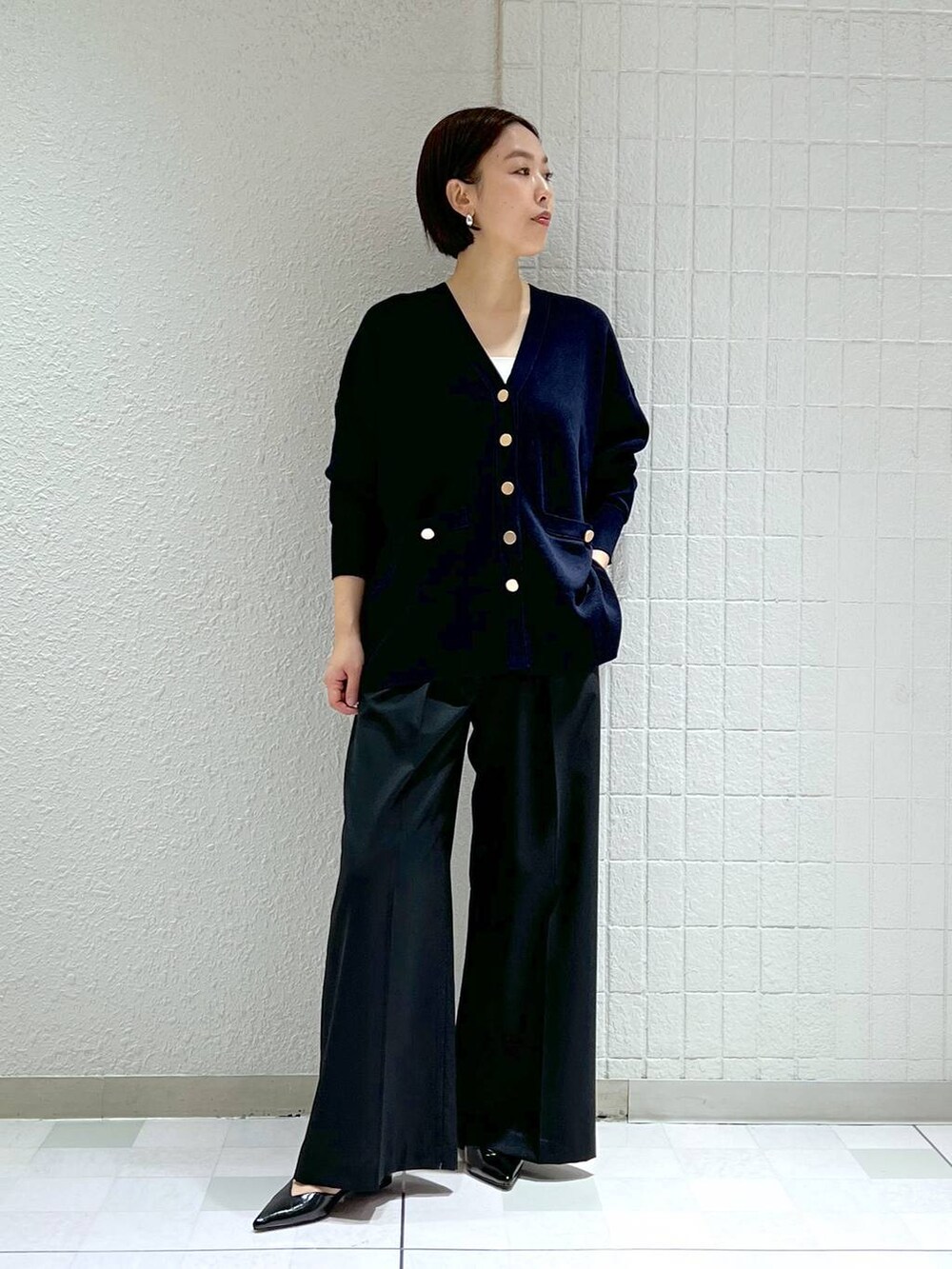 ブラック系のスラックス、ブラック系のパンプス、ブルー系のカーディガン/ボレロを着用したレディースの冬コーディネートの2枚目の写真