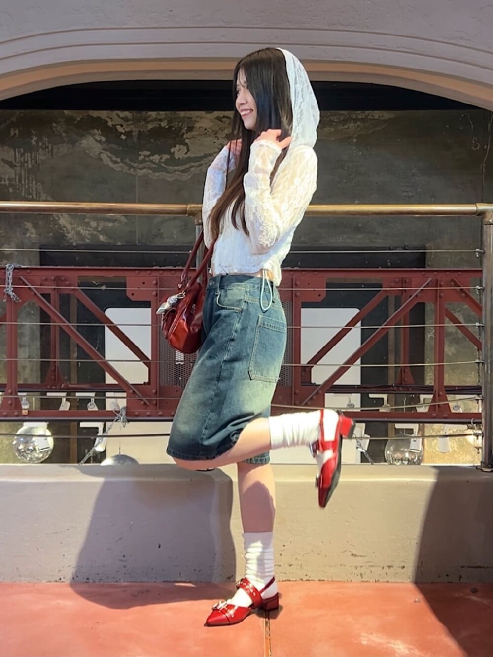 ホワイト系のキャミソール、ブルー系のデニムパンツ、レッド系のボストンバッグを着用したレディースの春コーディネートの2枚目の写真