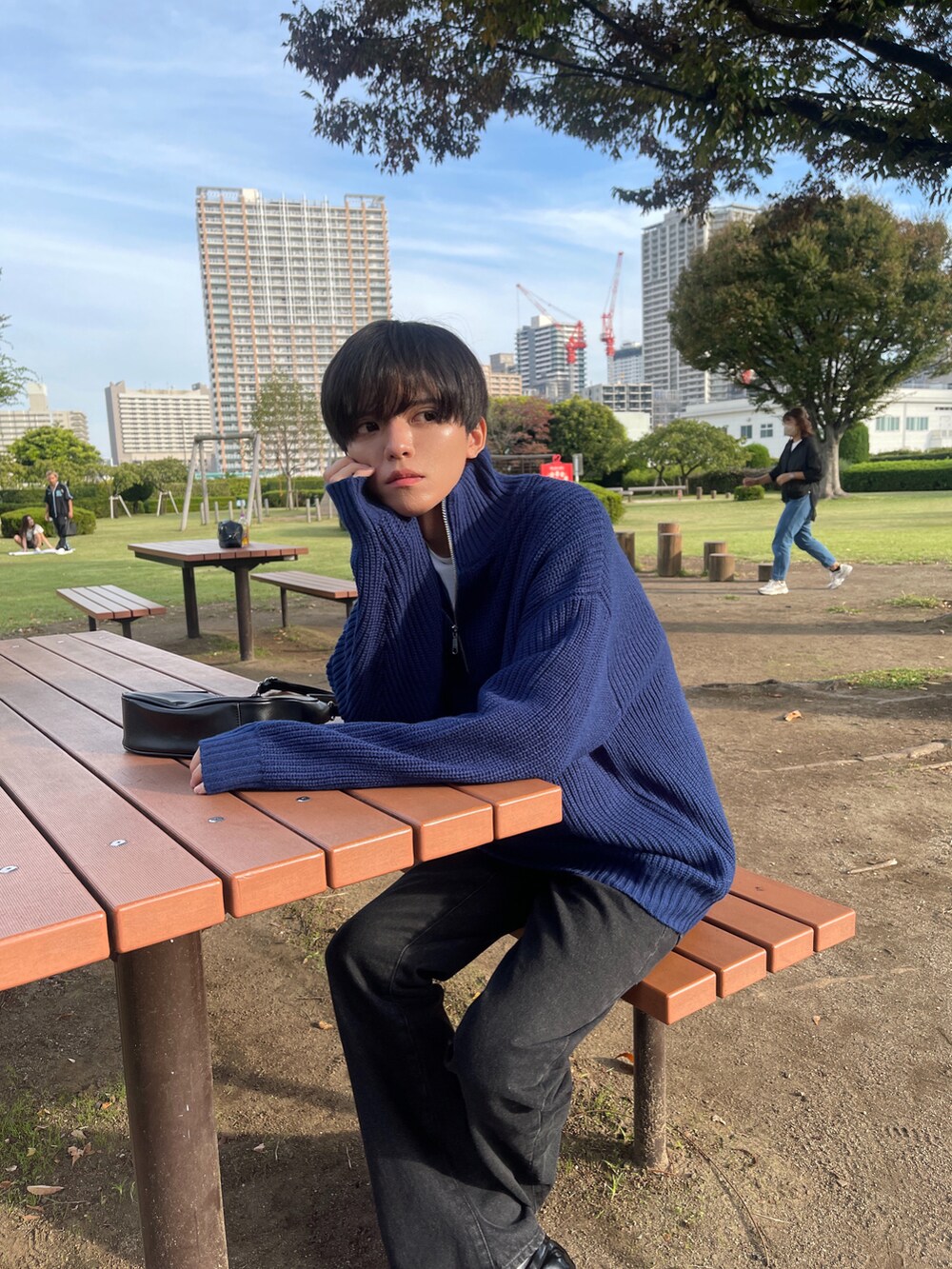 ブルー系のニット/セーター、ブラック系のデニムパンツ、ブラック系のショルダーバッグを着用したメンズの秋コーディネートの3枚目の写真