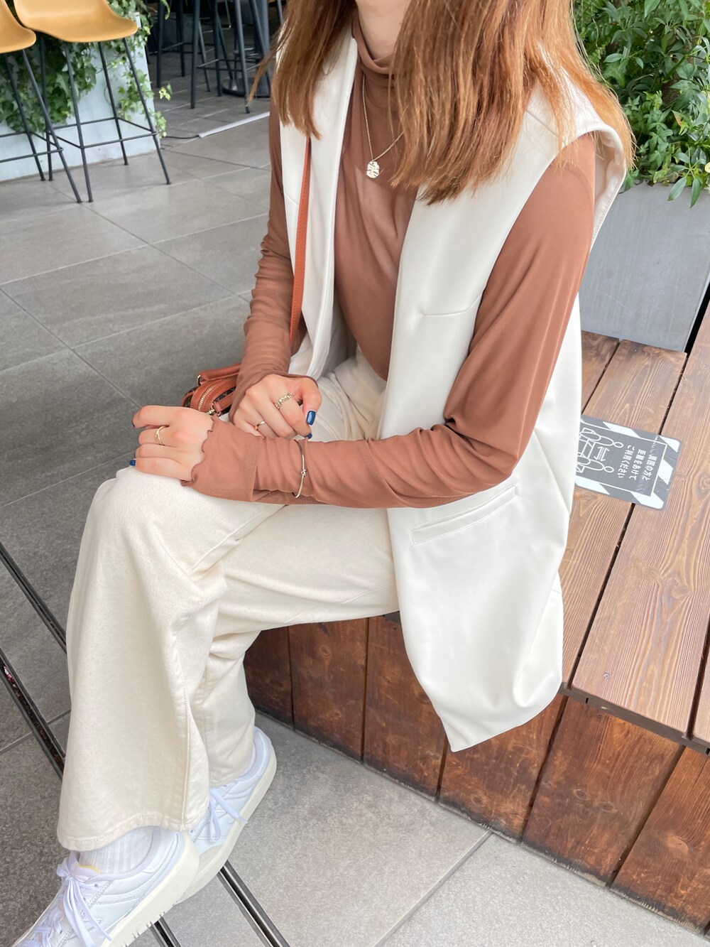 ホワイト系のベスト、ブラウン系のTシャツ/カットソー、ベージュ系のデニムパンツを着用したレディースの夏コーディネートの2枚目の写真