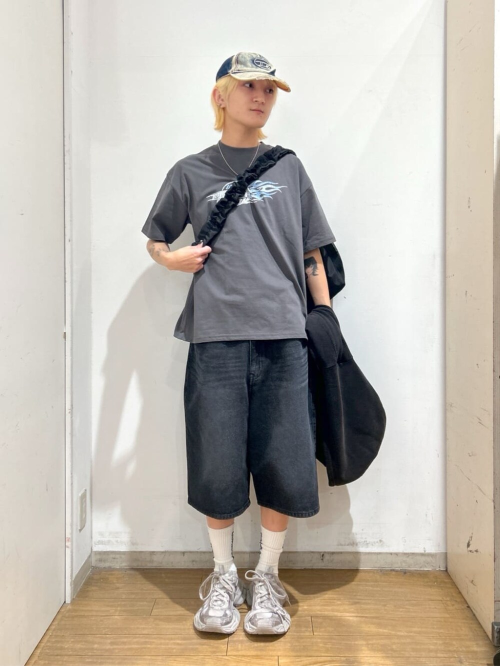 ブラック系のパーカー、ブラック系のショルダーバッグ、ブラック系のデニムパンツを着用したメンズの春コーディネートの2枚目の写真