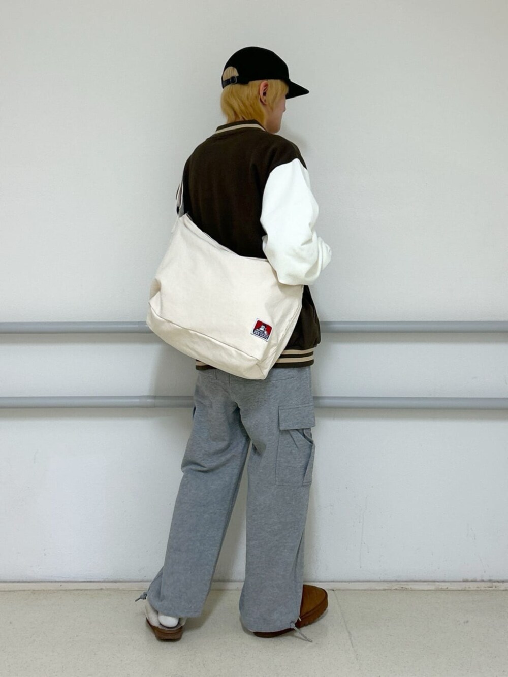 グレー系のカーゴパンツ、ブラウン系のスタジャン、ベージュ系のショルダーバッグを着用したメンズの冬コーディネートの2枚目の写真