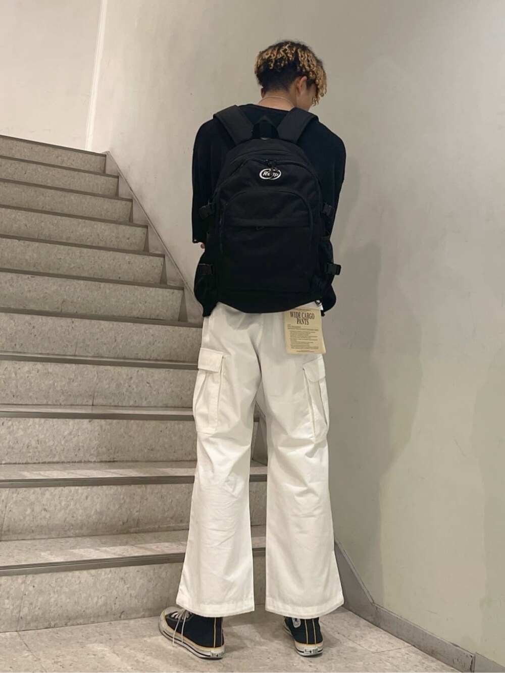 ホワイト系のカーゴパンツ、その他のバックパック/リュック、ブラック系のニット/セーターを着用したメンズの春コーディネートの2枚目の写真