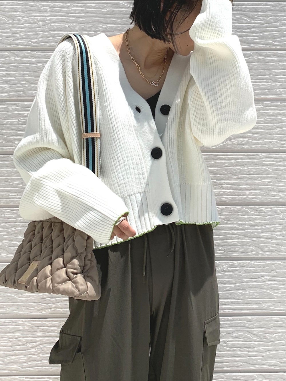 グリーン系のカーゴパンツ、ブラック系のスニーカー、ホワイト系のカーディガン/ボレロを着用したレディースの夏コーディネートの3枚目の写真
