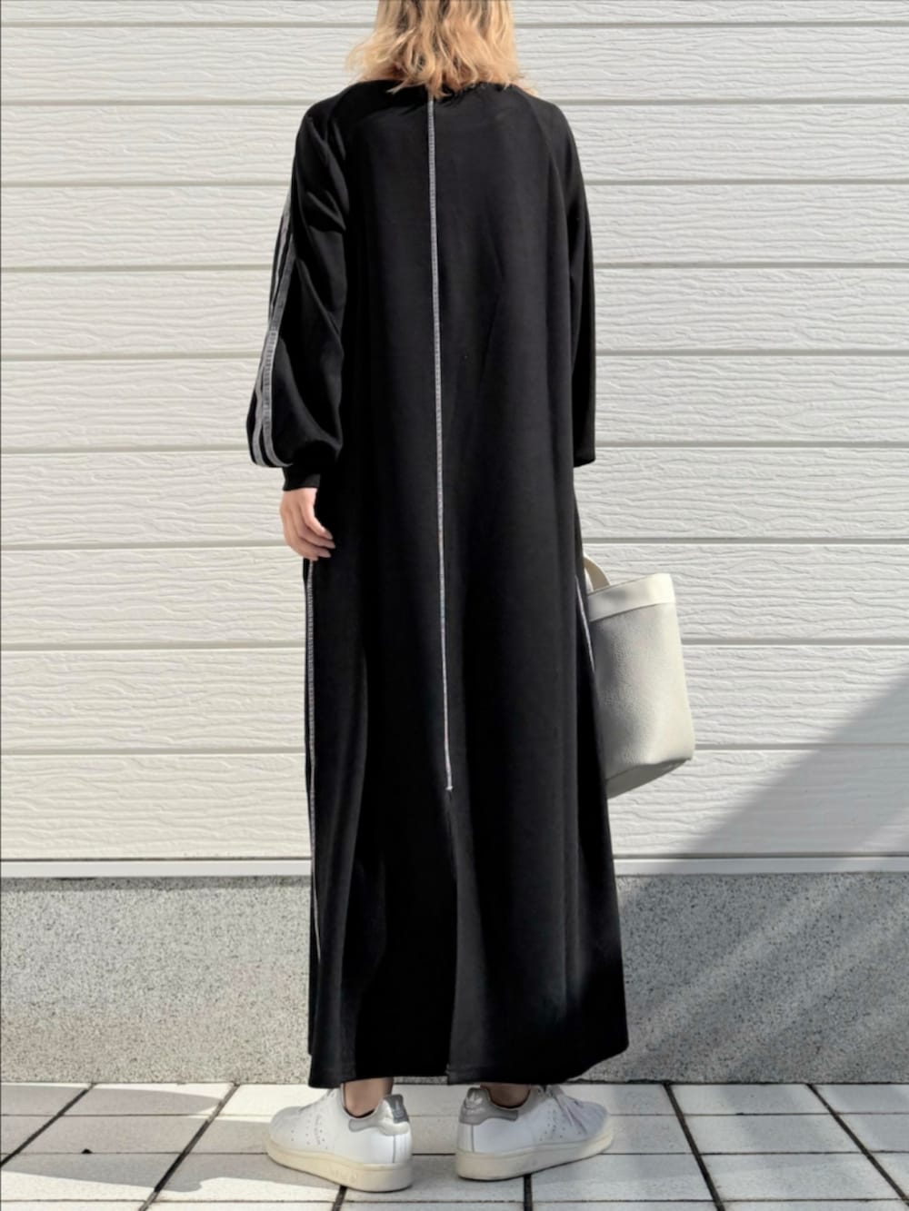 ホワイト系のスニーカー、ブラック系のワンピース、グレー系のトートバッグを着用したレディースの秋コーディネートの3枚目の写真