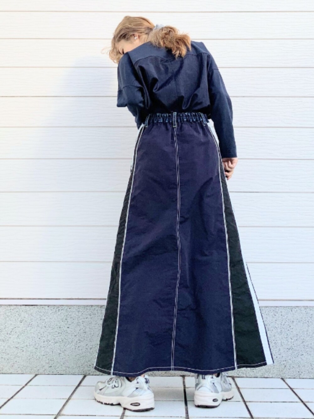 シルバー系のスニーカー、ブルー系のデニムスカート、ブルー系のTシャツ/カットソーを着用したレディースの冬コーディネートの3枚目の写真