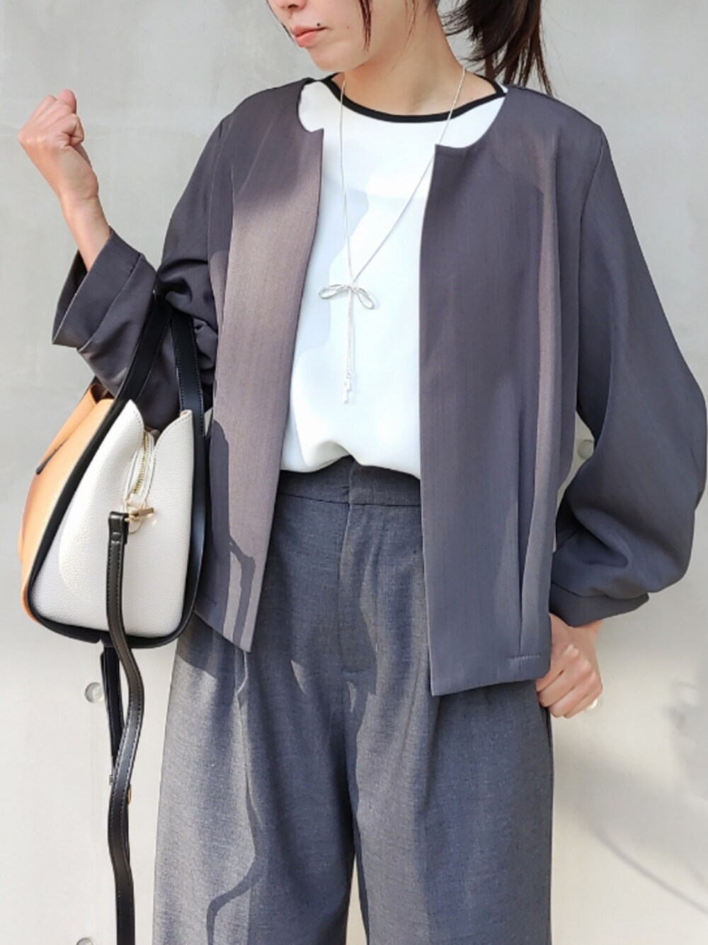 グレー系のスラックス、グレー系のノーカラージャケット、ホワイト系のシャツ/ブラウスを着用したレディースの冬コーディネートの3枚目の写真