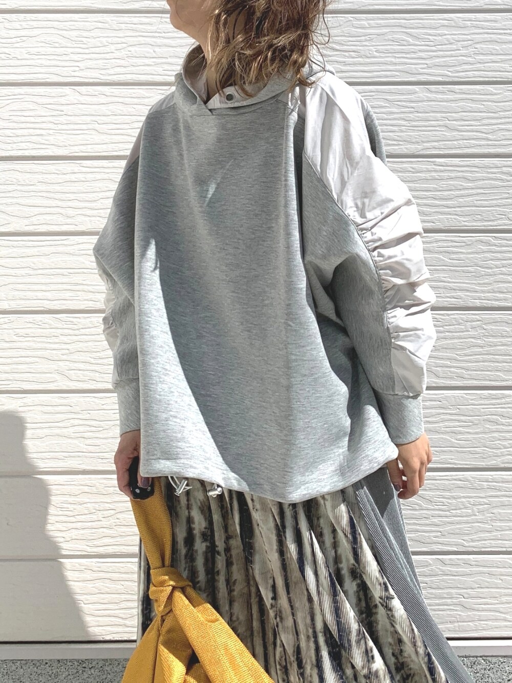 ホワイト系のスニーカー、ベージュ系のスカート、イエロー系のショルダーバッグを着用したレディースの春コーディネートの3枚目の写真