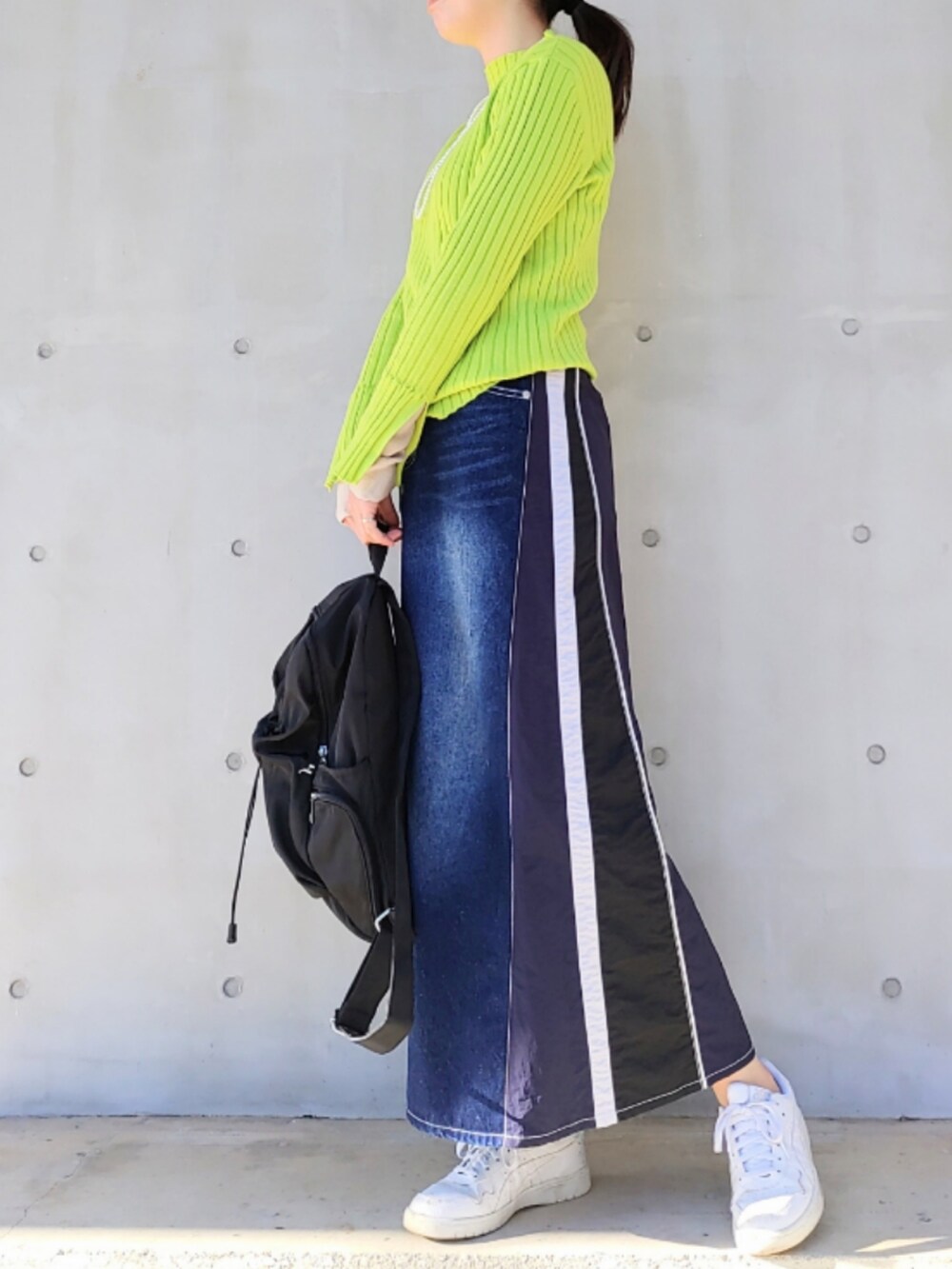 ブルー系のデニムスカート、グリーン系のニット/セーター、ブラック系のバックパック/リュックを着用したレディースの冬コーディネートの3枚目の写真