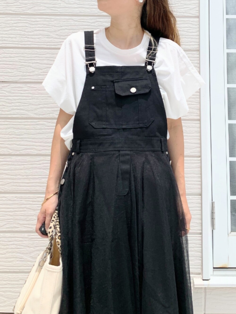 ホワイト系のスニーカー、ブラック系のジャンパースカート、ホワイト系のTシャツ/カットソーを着用したレディースの夏コーディネートの4枚目の写真