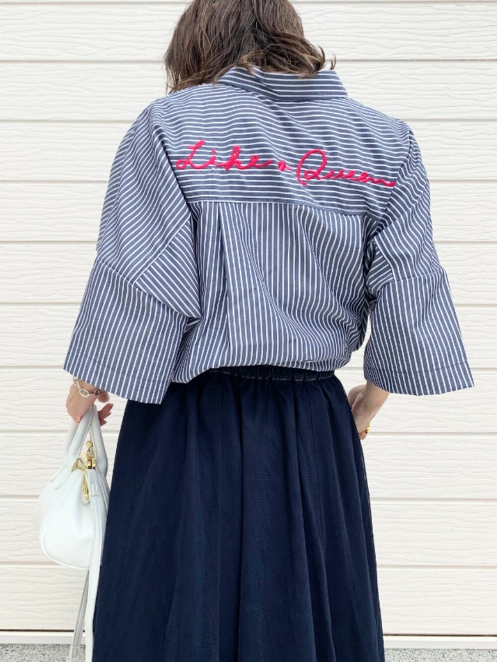 ブルー系のスカート、ホワイト系のショルダーバッグ、ブルー系のシャツ/ブラウスを着用したレディースの春コーディネートの3枚目の写真