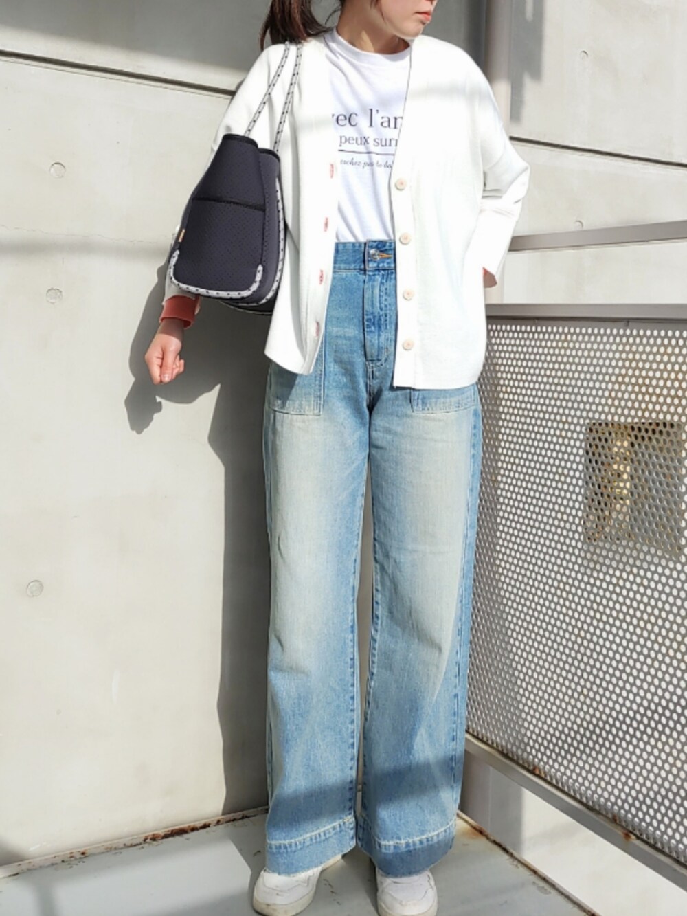 ブルー系のトートバッグ、ブルー系のデニムパンツ、ホワイト系のスニーカーを着用したレディースの冬コーディネートの3枚目の写真