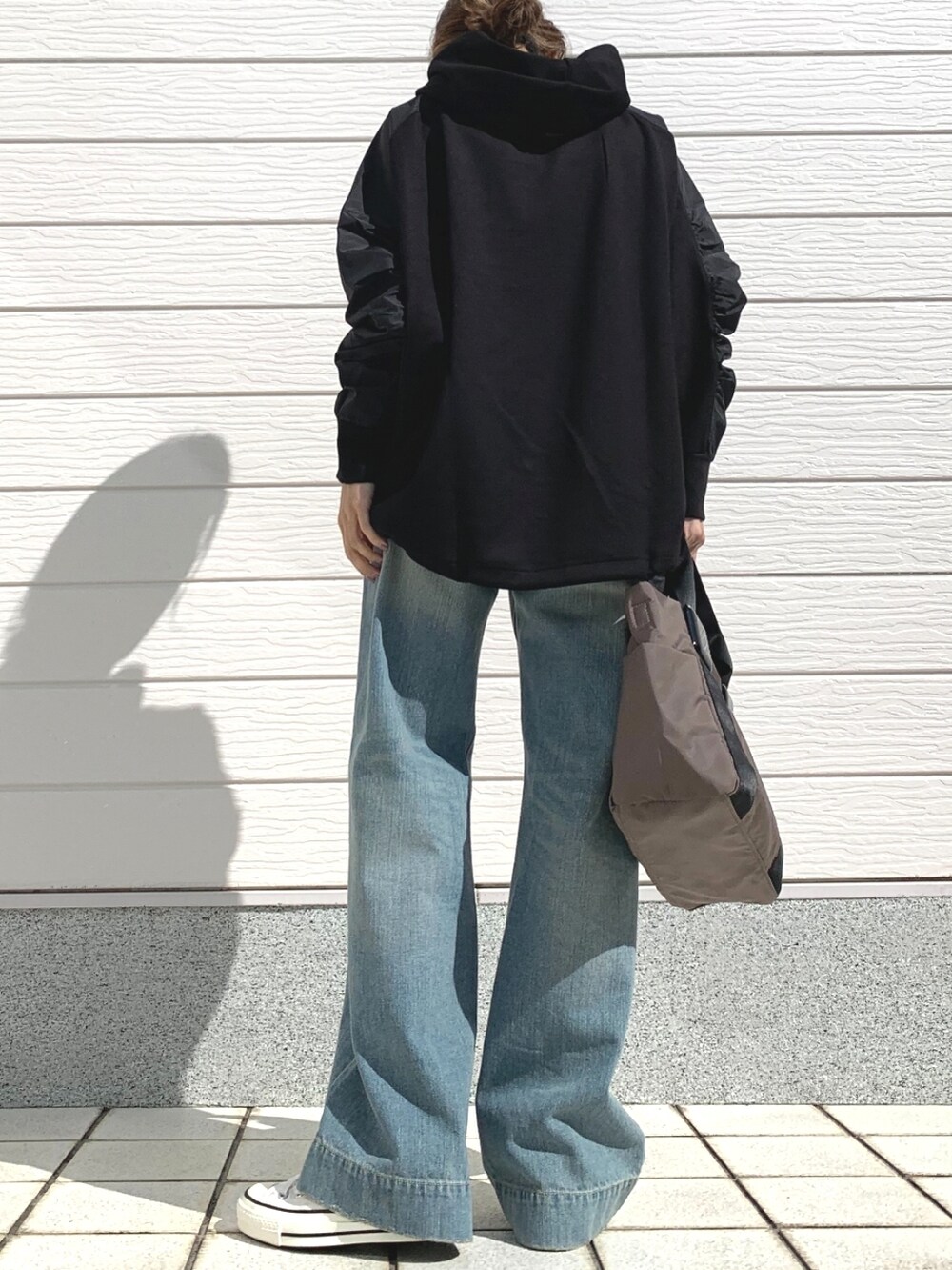 ブルー系のデニムパンツ、グリーン系のトートバッグ、ホワイト系のスニーカーを着用したレディースの春コーディネートの2枚目の写真