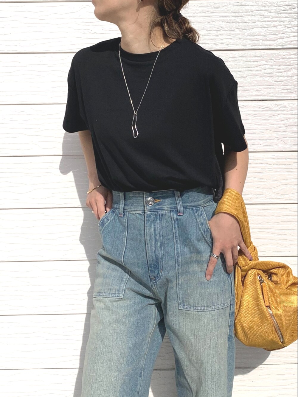 ブルー系のデニムパンツ、ブラック系のサンダル、イエロー系のショルダーバッグを着用したレディースの春コーディネートの2枚目の写真