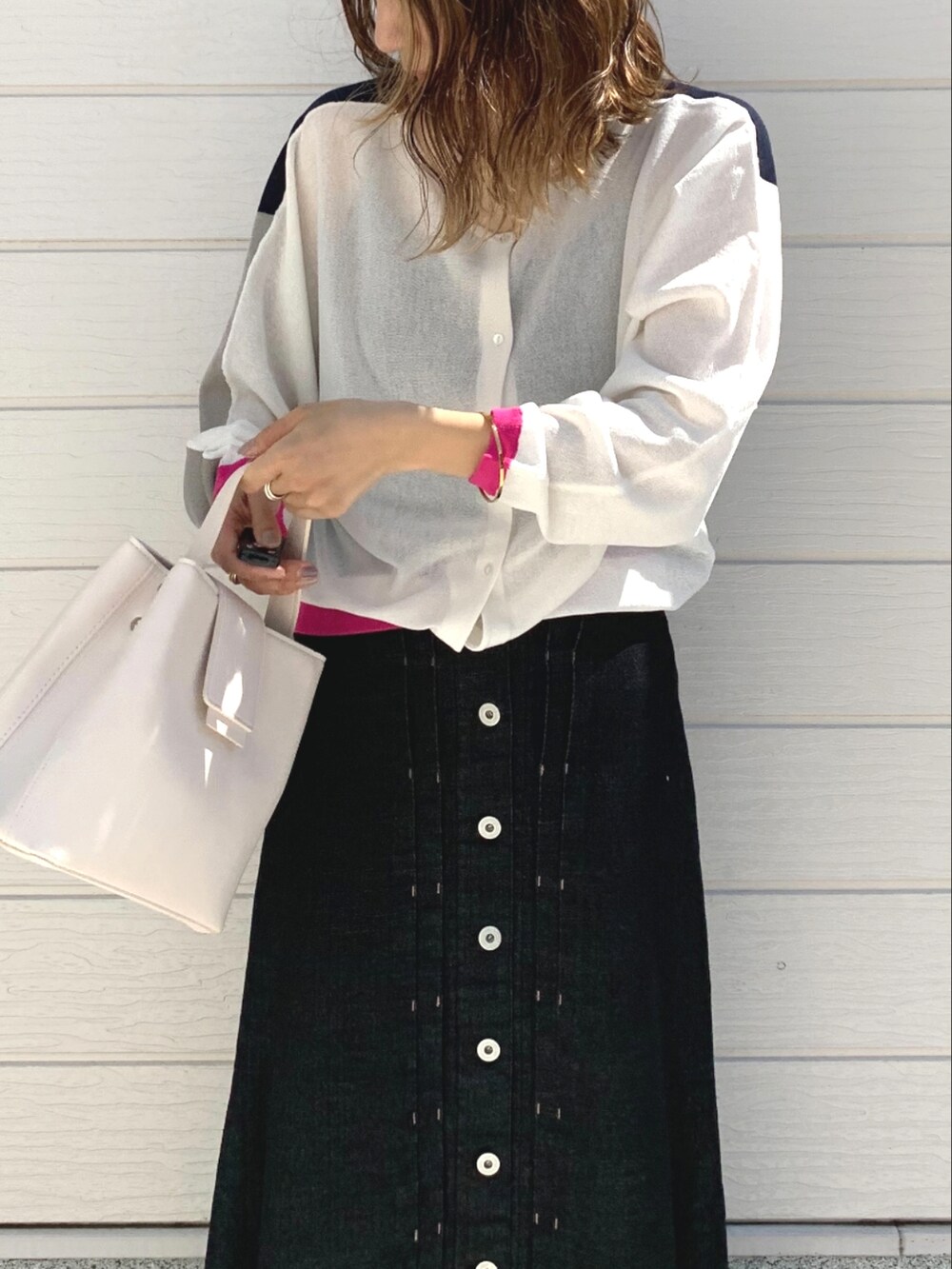 ホワイト系のハンドバッグ、ブラック系のデニムスカート、ホワイト系のカーディガン/ボレロを着用したレディースの春コーディネートの3枚目の写真