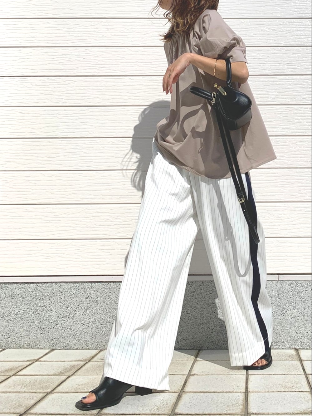 ブラック系のショルダーバッグ、ホワイト系のその他パンツ、ブラック系のサンダルを着用したレディースの春コーディネートの2枚目の写真