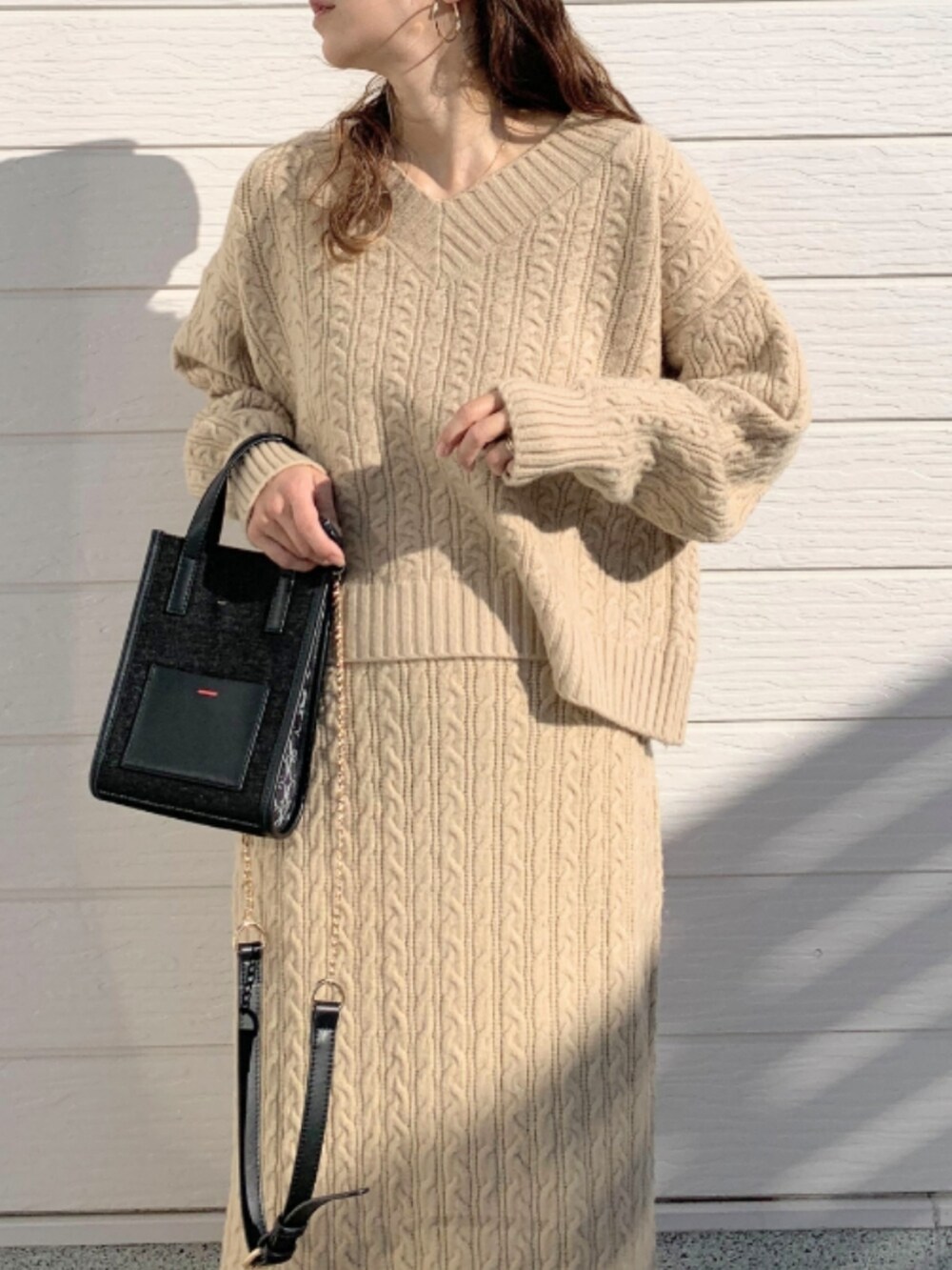 ブラック系のショルダーバッグ、ホワイト系のスニーカー、ベージュ系のニット/セーターを着用したレディースの冬コーディネートの4枚目の写真