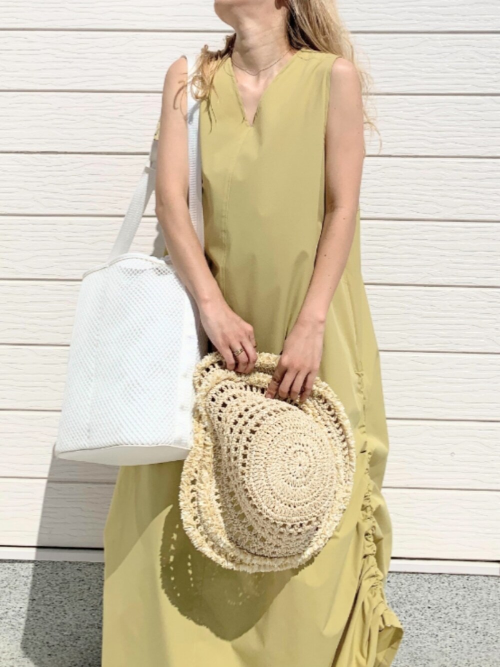 ブルー系のデニムパンツ、イエロー系のワンピース、ホワイト系のショルダーバッグを着用したレディースの春コーディネートの5枚目の写真