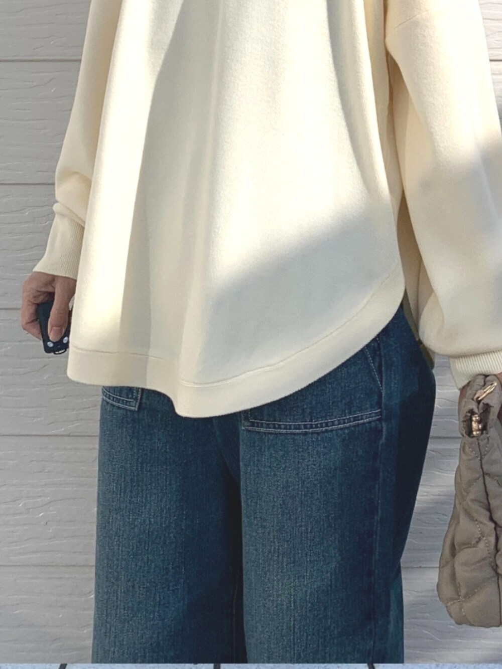 ベージュ系のショルダーバッグ、ブルー系のデニムパンツ、ホワイト系のニット/セーターを着用したレディースの冬コーディネートの3枚目の写真