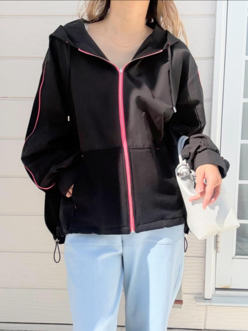 ブルー系のデニムパンツ、ブラック系のパーカー、シルバー系のトートバッグを着用したレディースの春コーディネートの4枚目の写真