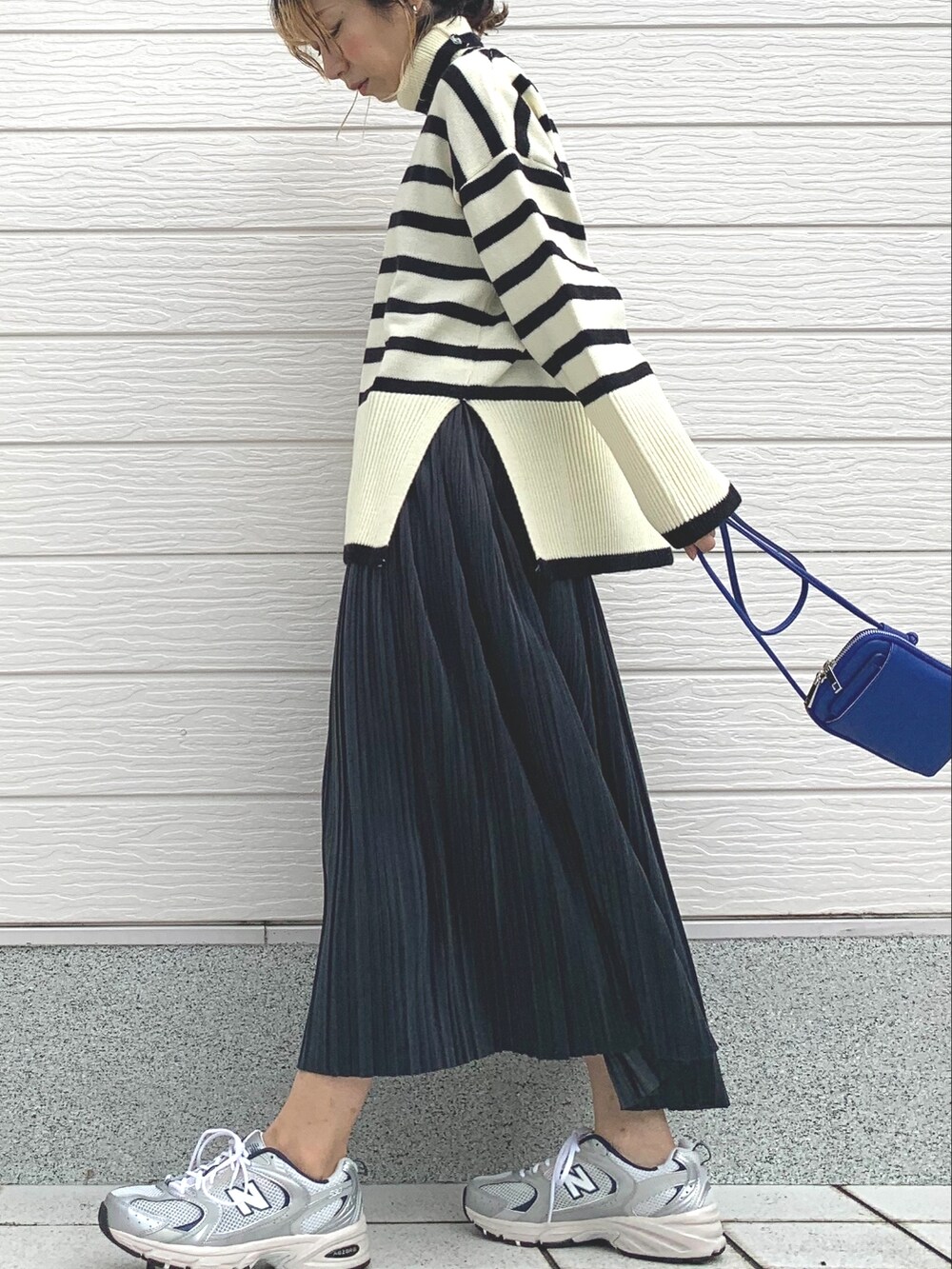 シルバー系のスニーカー、ブルー系のショルダーバッグ、ホワイト系のニット/セーターを着用したレディースの秋コーディネートの2枚目の写真