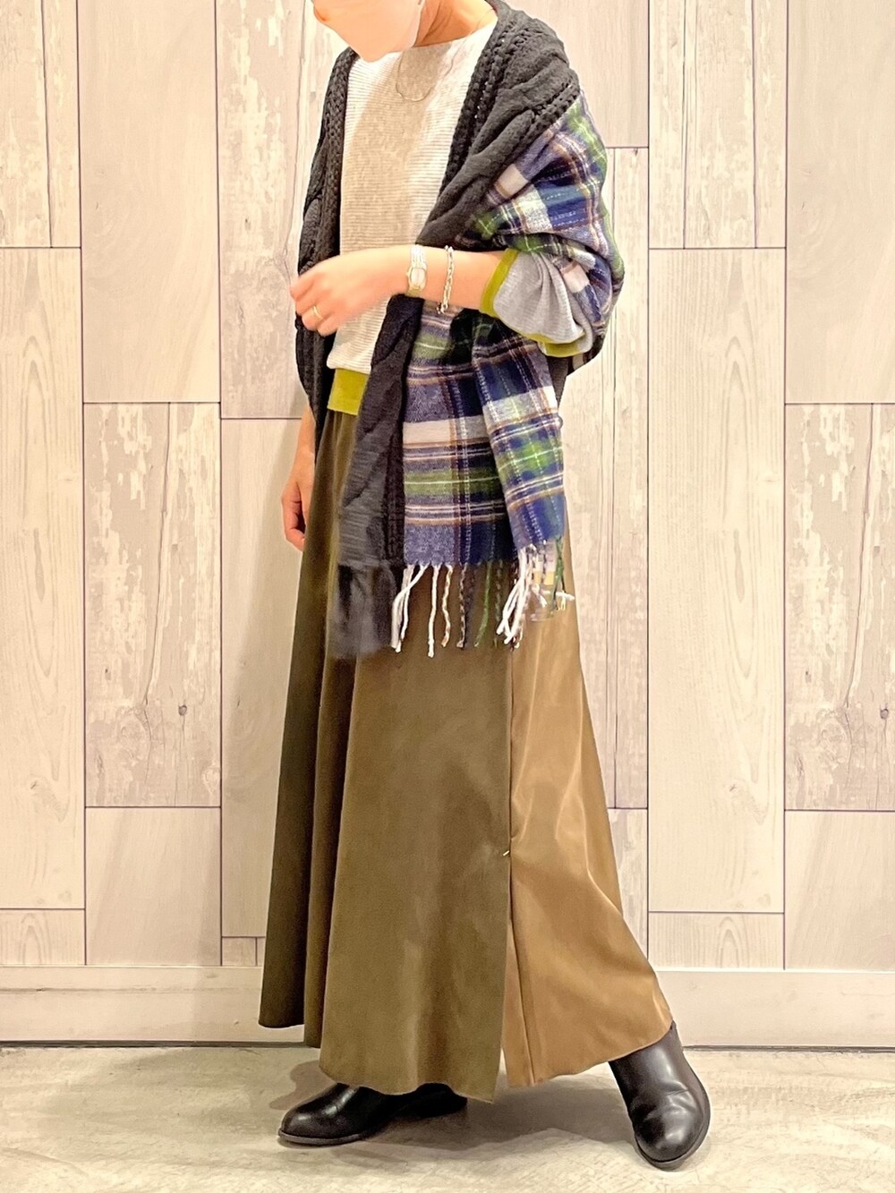 グレー系のニット/セーター、グリーン系のスカート、ブラック系のストール/ショールを着用したレディースの秋コーディネートの2枚目の写真
