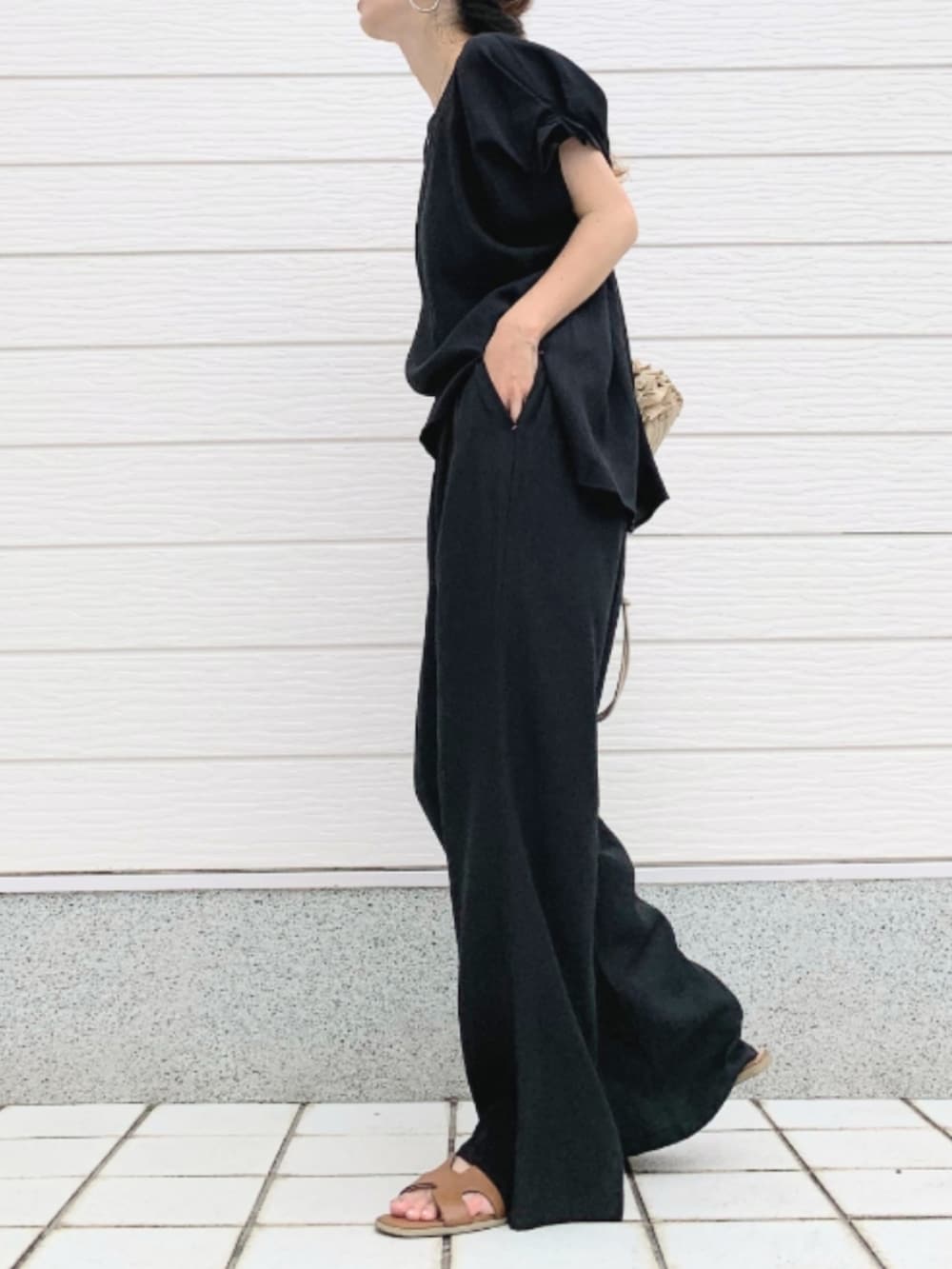 ベージュ系のクラッチバッグ、イエロー系のサンダル、ブラック系のシャツ/ブラウスを着用したレディースの夏コーディネートの2枚目の写真