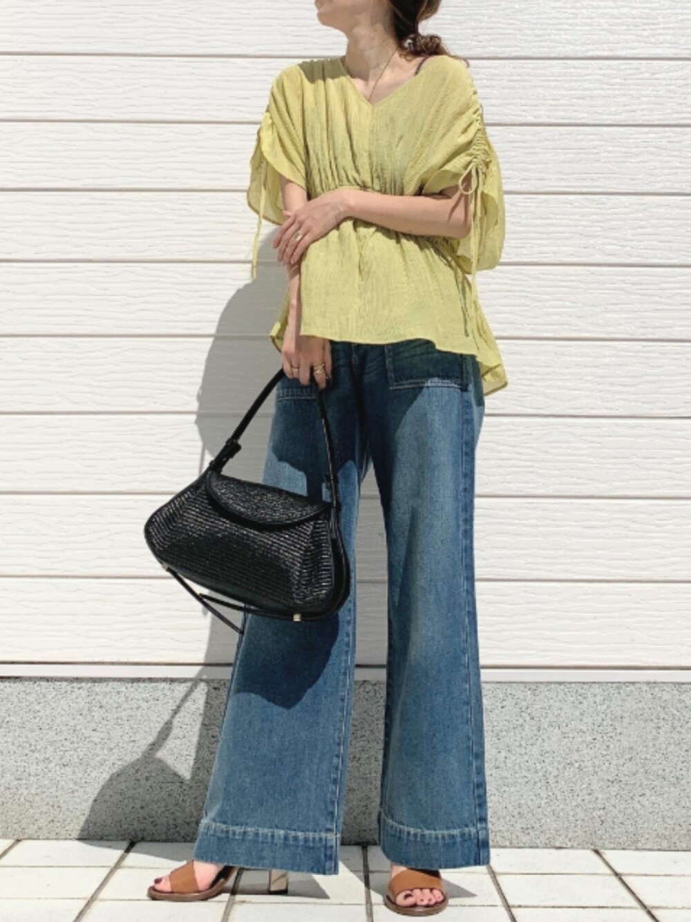 ブラック系のショルダーバッグ、ブラウン系のサンダル、イエロー系のシャツ/ブラウスを着用したレディースの春コーディネートの2枚目の写真