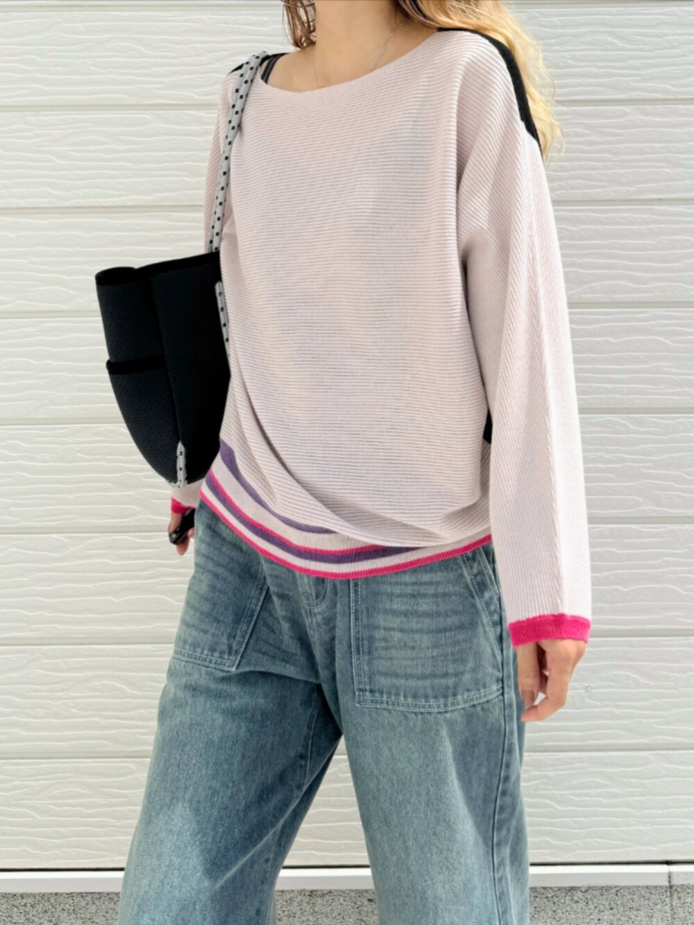 ブルー系のデニムパンツ、ブラック系のニット/セーター、ブルー系のトートバッグを着用したレディースの秋コーディネートの5枚目の写真