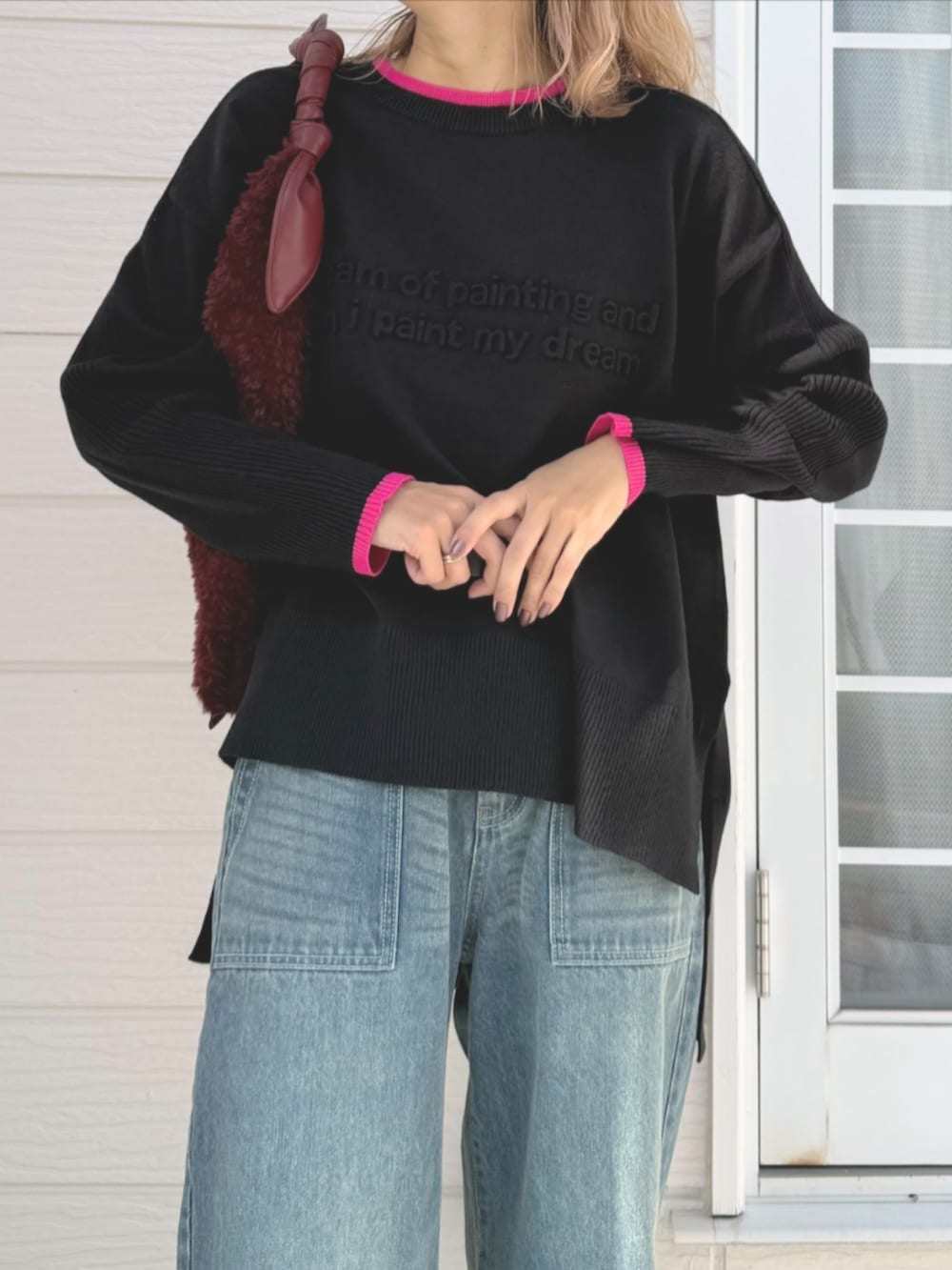 レッド系のトートバッグ、ブルー系のデニムパンツ、ブラック系のニット/セーターを着用したレディースの秋コーディネートの4枚目の写真