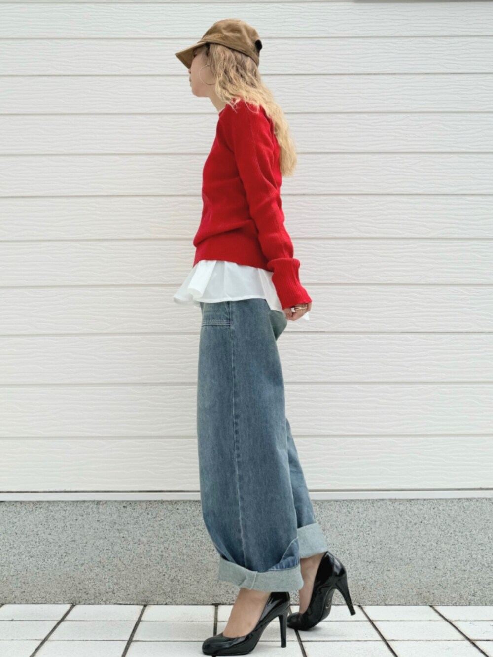 レッド系のニット/セーター、ブルー系のデニムパンツ、ホワイト系のTシャツ/カットソーを着用したレディースの秋コーディネートの2枚目の写真