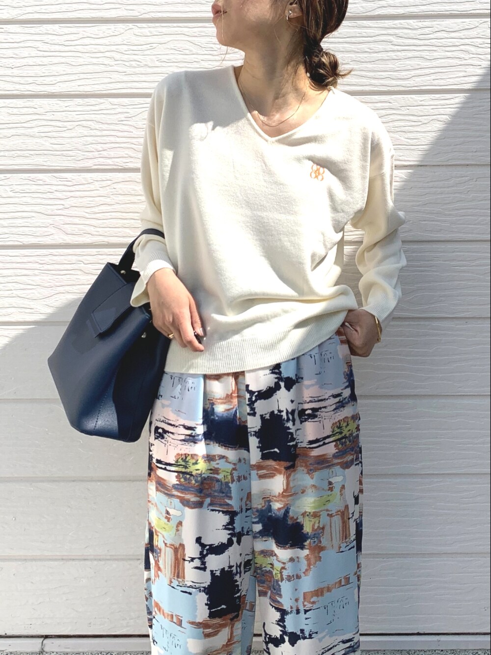 ブルー系のハンドバッグ、ホワイト系のニット/セーター、ブルー系のその他パンツを着用したレディースの春コーディネートの3枚目の写真