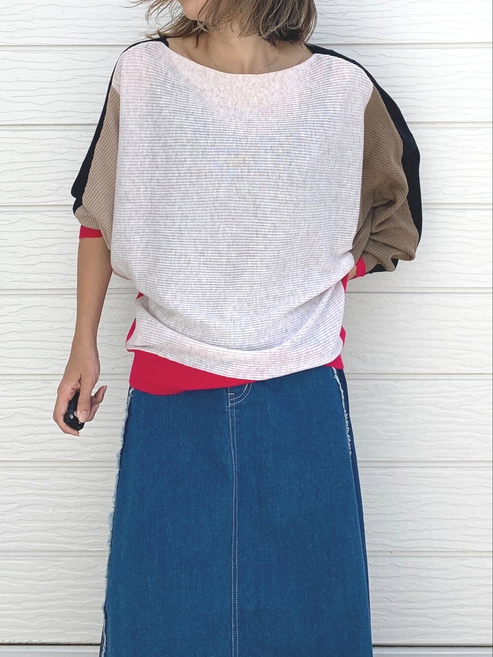 ブルー系のデニムスカート、ブラック系のスニーカー、ブラック系のニット/セーターを着用したレディースの夏コーディネートの4枚目の写真