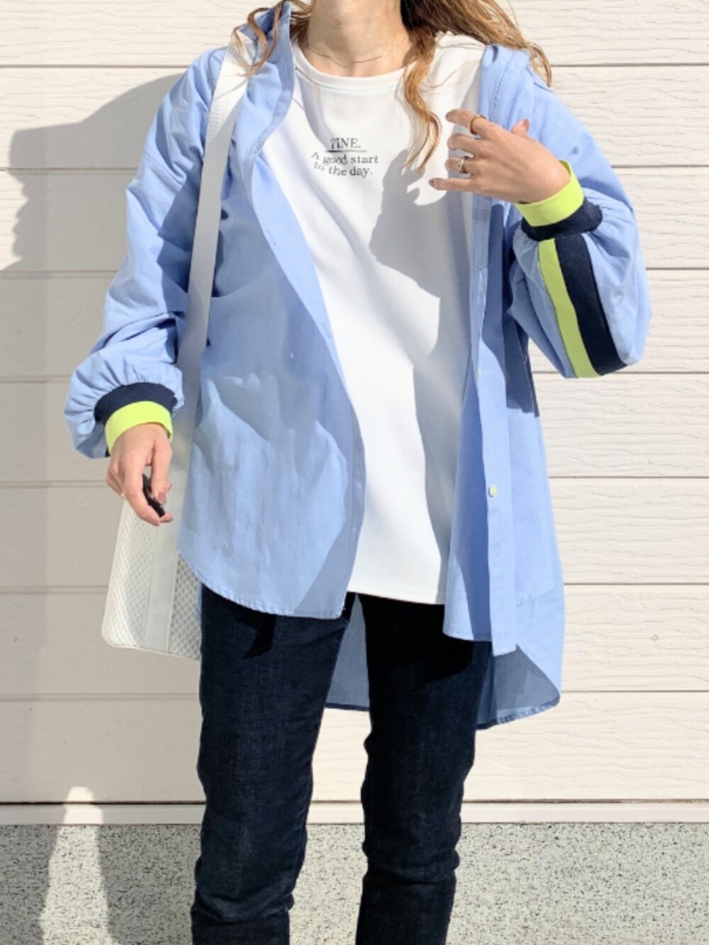 ブルー系のデニムパンツ、シルバー系のスニーカー、ホワイト系のショルダーバッグを着用したレディースの冬コーディネートの4枚目の写真