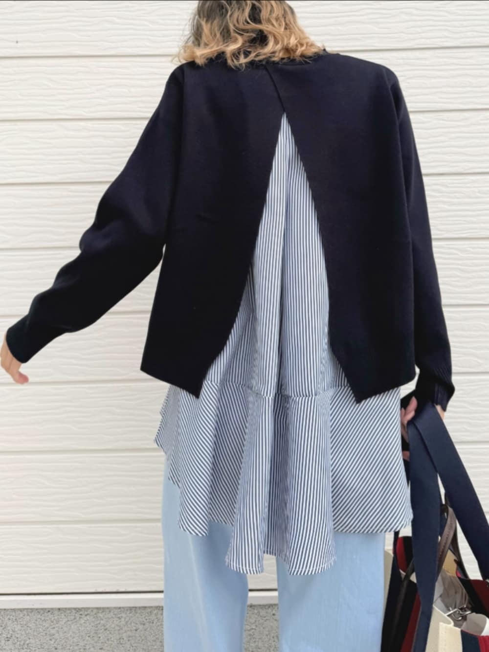 ブルー系のデニムパンツ、ブルー系のニット/セーター、ブラック系のサンダルを着用したレディースの春コーディネートの5枚目の写真