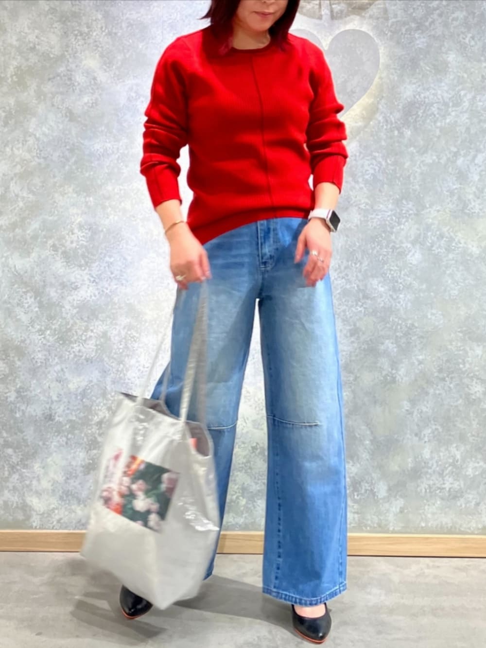 シルバー系のトートバッグ、ブルー系のデニムパンツ、レッド系のニット/セーターを着用したレディースの秋コーディネートの2枚目の写真