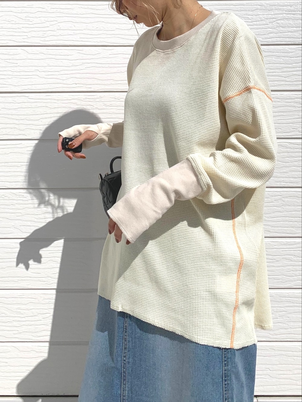 ブラック系のドラムバッグ、ブルー系のデニムスカート、ホワイト系のTシャツ/カットソーを着用したレディースの秋コーディネートの3枚目の写真